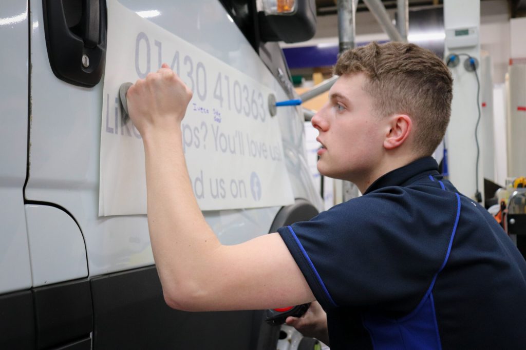 Blaine applying signage to a van.